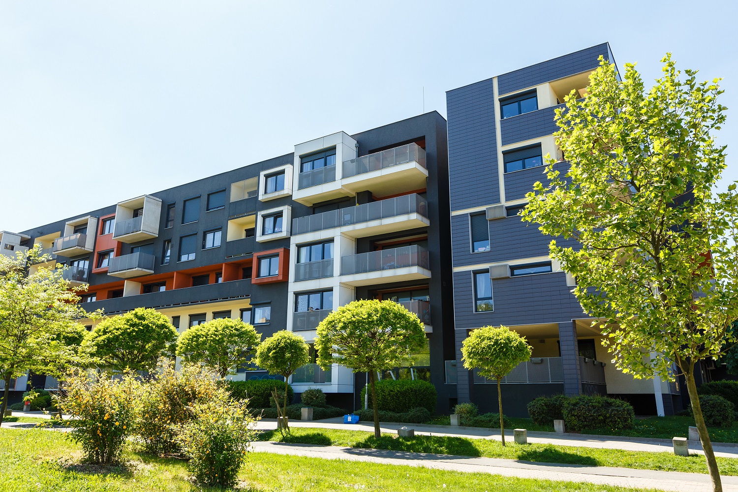 Exterior Of A Modern Black Apartment Buildings On A Blue Sky Bac